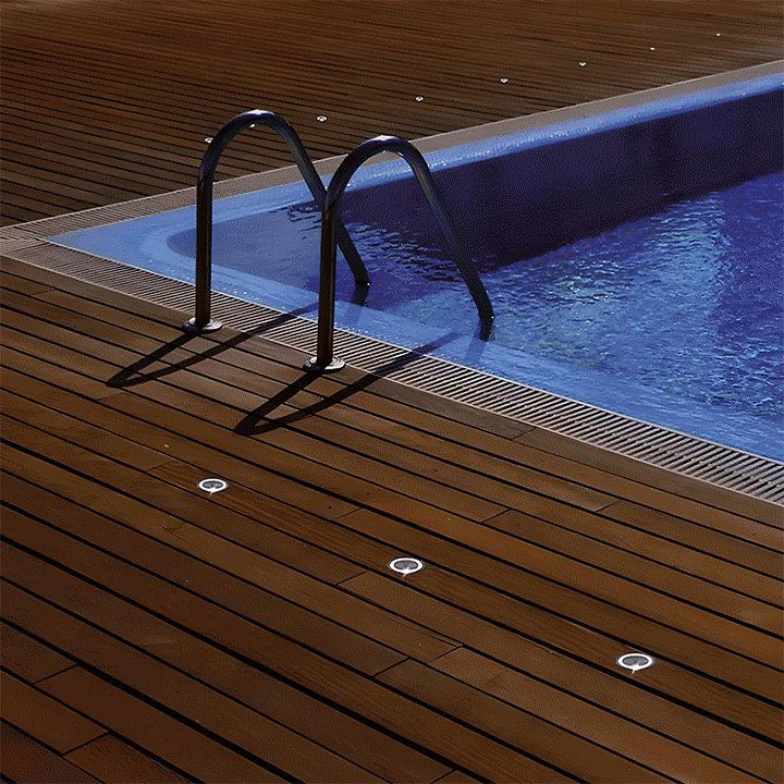 Image d'une piscine entourée d'une terrasse bois avec des spots intégrés