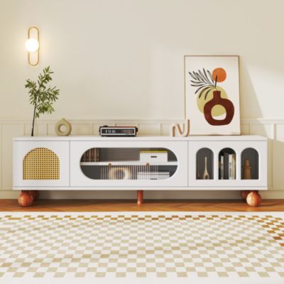 Meuble TV avec porte en rotin, porte en verre coulissante, trois compartiments ouverts, poignées dorées et pieds en bois massif.