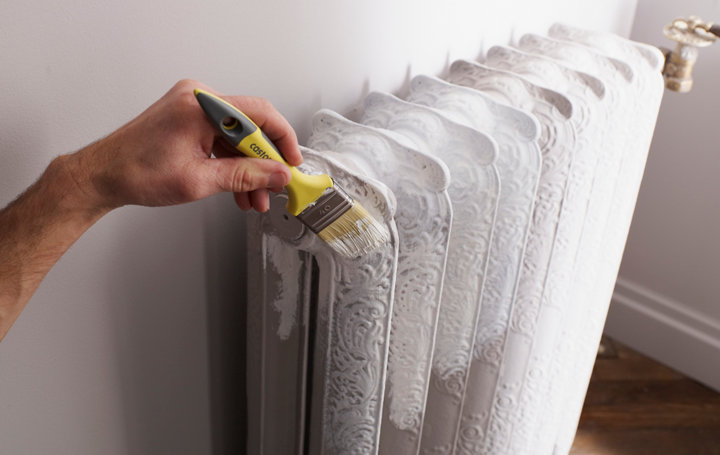 Personne peignant un radiateur en blanc