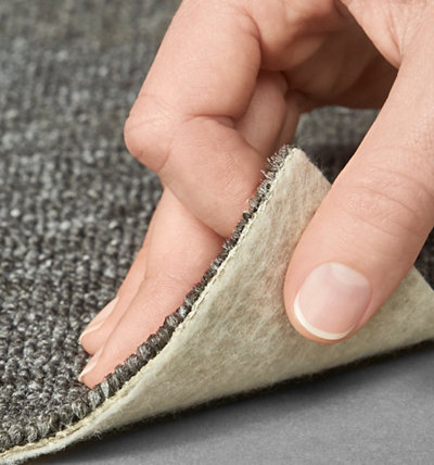personne soulevant bord dalle moquette grise