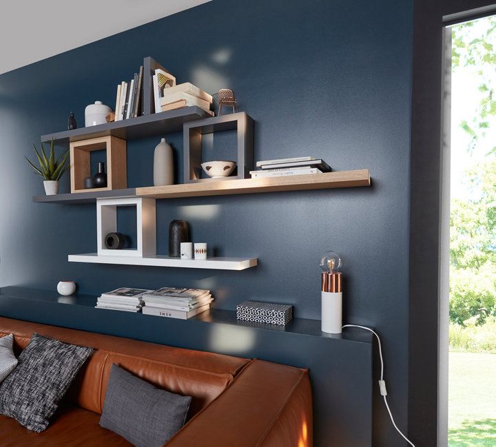 Tablettes murales différentes couleurs avec déco au dessus d'un canapé
