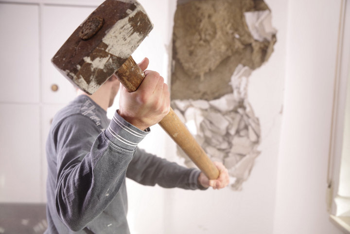 Personne abattant un mur avec une masse