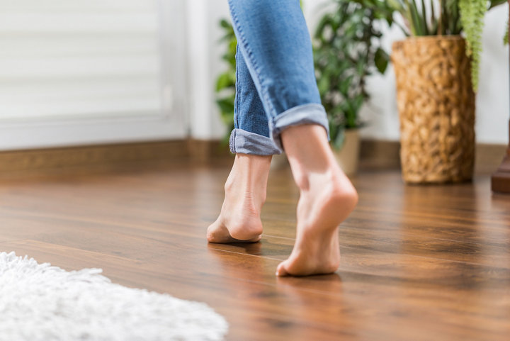 Une femme marche pieds nus sur un parquet