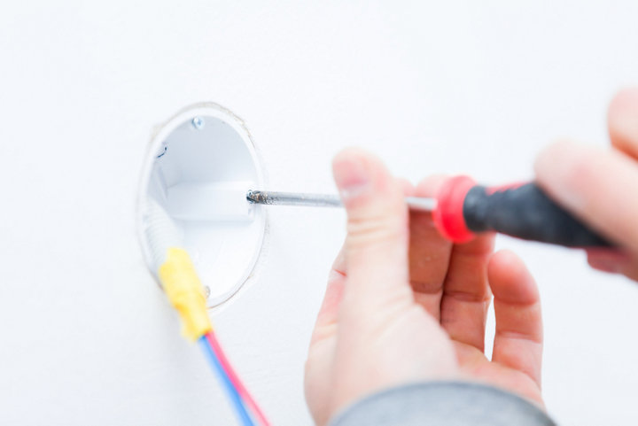 Personne fixant au mur une boite d'encastrement