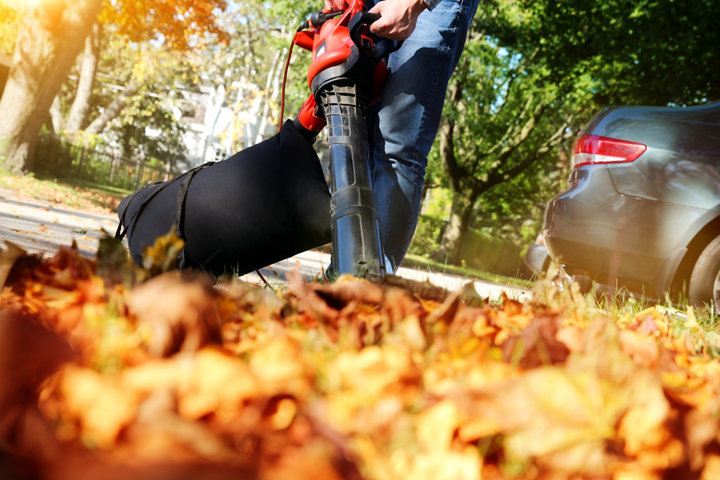 Personne soufflant des feuilles dans sont allée