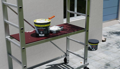 un échaffaudage devant un mur de maison avec un pot de peinture façade dessus