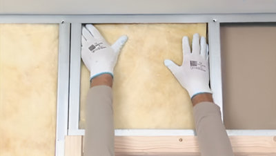 Installation de l'isolant sur la plaque dans l'ossature en haut de la porte