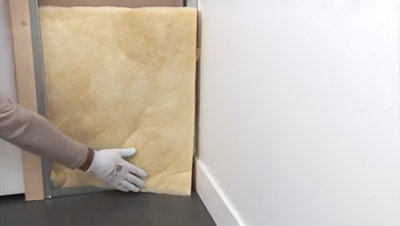 Installation de l'isolant sur la plaque dans l'ossature en bas de la porte