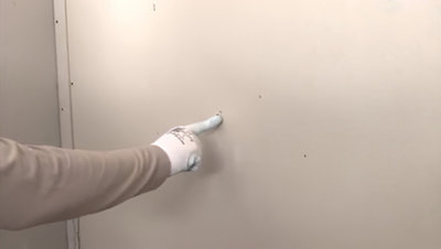 Personne touchant du doigt la plaque de plâtre au mur