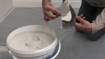 Personne qui prend de l'enduit dans le pot avec ses spatules