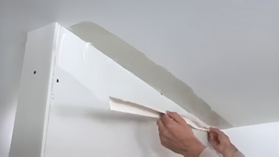 Personne qui applique la bande à joint sur le mur