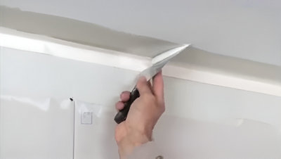 Personne qui serre la bande à joint au mur avec une spatule