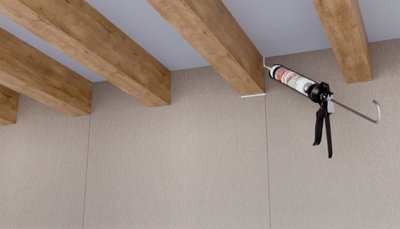 Application du mastic sur les angles entre poutre bois et mur