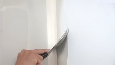 Personne qui lisse le mur avec une spatule