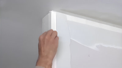 Personne qui applique une bande de pliage en haut du mur