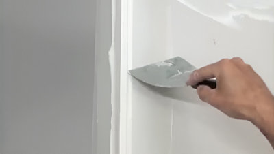 Personne qui lisse la bande avec un couteau à enduire