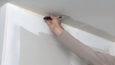 Personne qui applique de l'enduit avec spatule au plafond