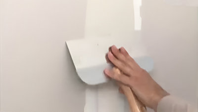 Utilisation d'une grande spatule sur le mur au niveau de l'enduit
