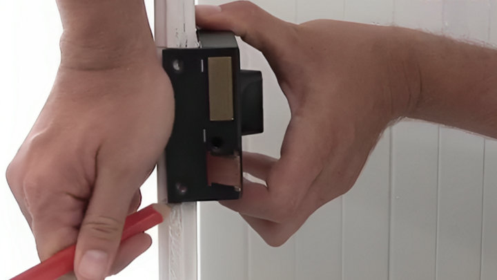 Traçage des repères de la nouvelle serrure sur la porte avec un crayon