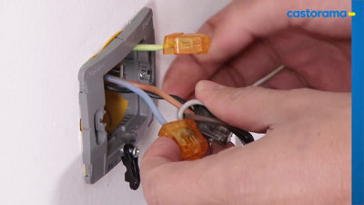 Raccordement des fils électriques (phase, neutre, terre) avec des bornes Wago dans une boîte d'encastrement.