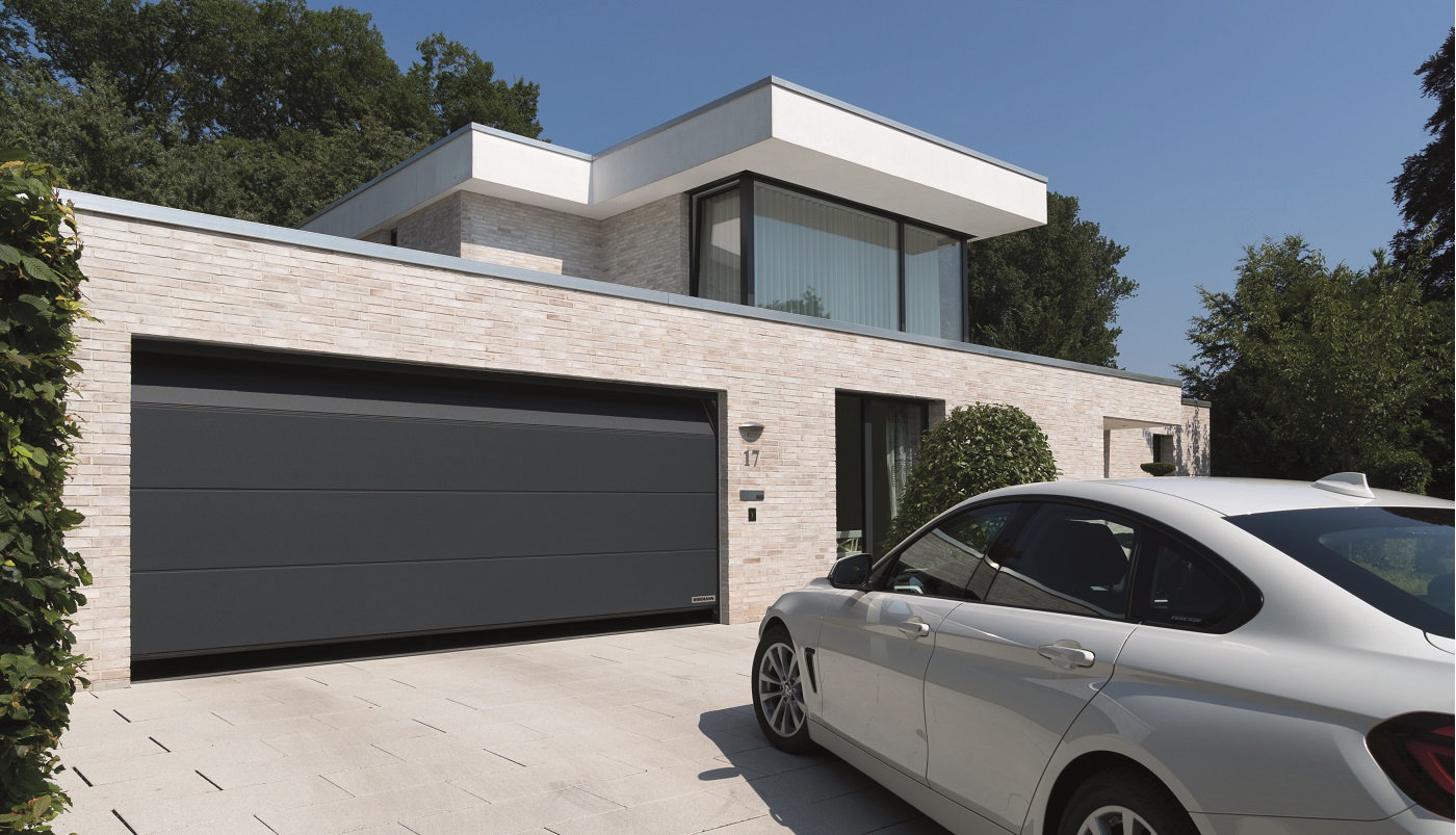 Une grande porte de garage sectionnelle s'ouvre pour laisser un véhicule se garer