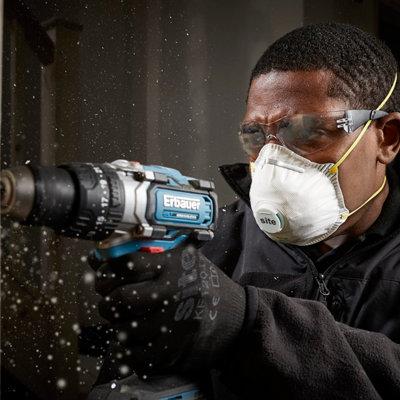Un homme en plein perçage avec un masque et des lunettes de protection