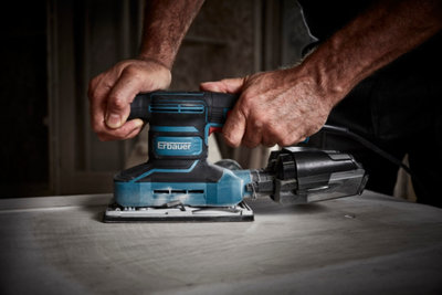Zoom sur des mains qui manipulent une ponceuse sur du bois