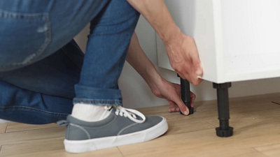 Une fois les deux meubles en place, utilisez les pieds à visser pour les ajuster sur la ligne de 87 cm.​