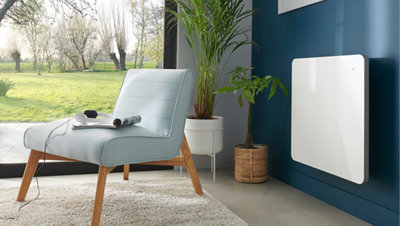Radiateur blanc sur un mur bleu dans une pièce avec fauteuil et grande fenêtre