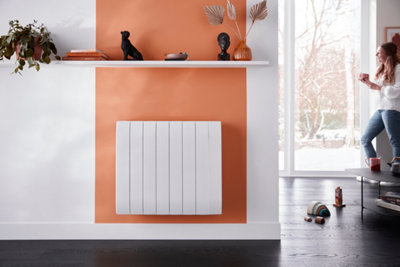 Radiateur à inertie sèche installé sur un mur coloré dans une pièce à vivre lumineuse : confort thermique et chaleur douce.