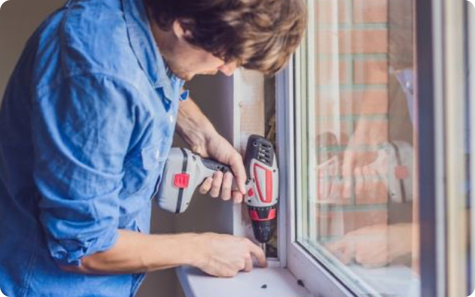 Personne installant une fenêtre avec une perceuse