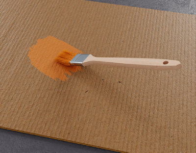 Passage pinceau avec peinture orange sur bout de carton