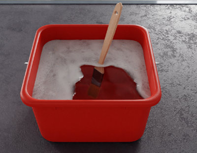 Pinceau trempé dans un seau et savon d'eau rouge
