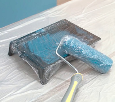 Rouleau et bac de peinture bleu avec du papier film par-dessus