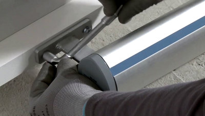 Fixe la patte aluminium de fixation à l’aide avec une clé à pipe.