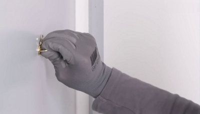 personne fixant avec une pièce de monnaie le judas