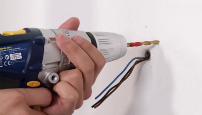 Perçage du mur à la perceuse pour installer des chevilles de fixation.