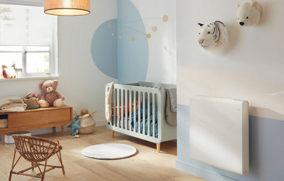Radiateur électrique connecté blanc installé dans une chambre de bébé pour un confort thermique optimal.