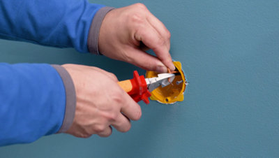 Personne utilisant pince sur fils sortant du mur