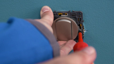 Personne vissant interrupteur au mur