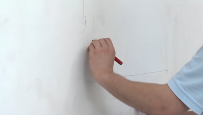 Personne marquant un repère au crayon sur mur