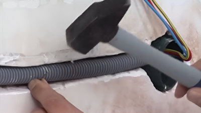 Fixation de la gaine dans saignée avec marteau et clou