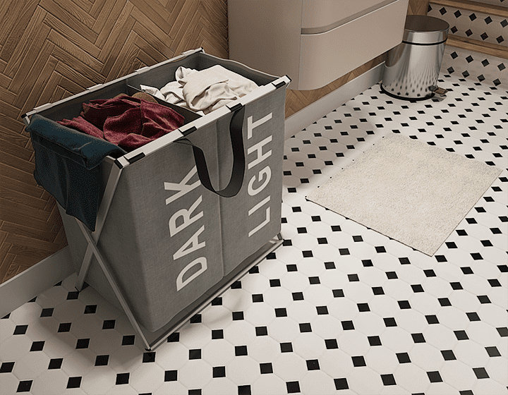 Panier à linge gris séparé noir et blanc sur sol carrelé noir et blanc