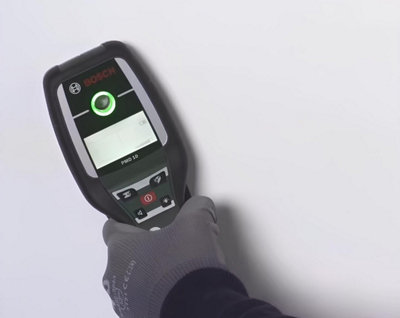 A l'aide d'un détecteur de métaux, vérification du mur avant perçage