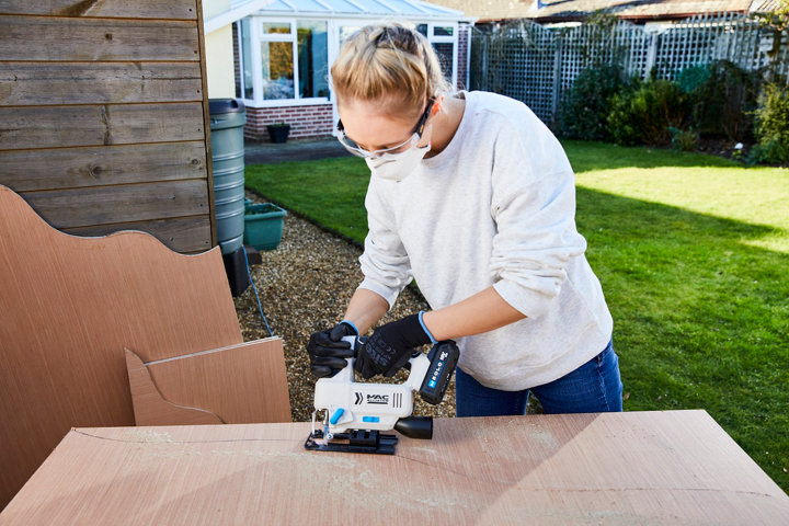 Une femme utilise une scie sauteuse sur une planche de bois