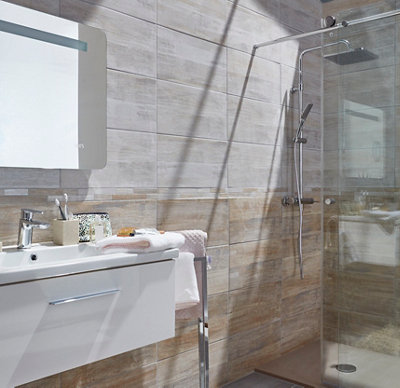 Salle de bain avec douche vitrée, carrelage bicolore et meuble vasque.
