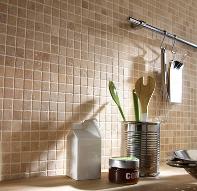 Crédence en mosaïque beige avec ustensiles de cuisine dans une boîte métallique.