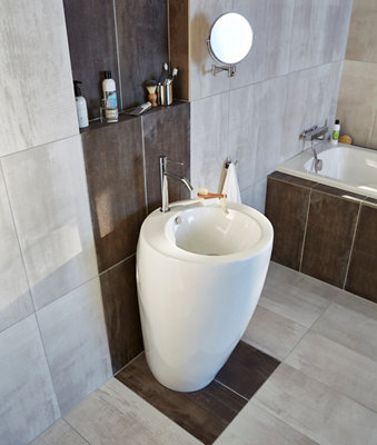Lavabo en forme de colonne et un mur en carrelage bicolore contrasté.