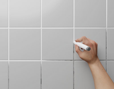 Carrelage mural avec une main qui rénove le joint