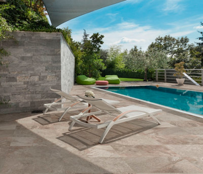 Une terrasse en dalles de pierre autour d'une piscine sous le soleil